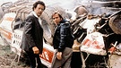 Effendi (Robert Giggenbach) und Sepp (Elmar Wepper) stehen vor dem zertrümmerten Bus. | Bild: BR/Tellux-Film